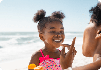 Smiling baby at the beach with sand and waves in the background